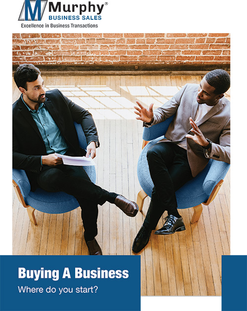 Person reviewing a checklist for buying a business with a laptop and business documents